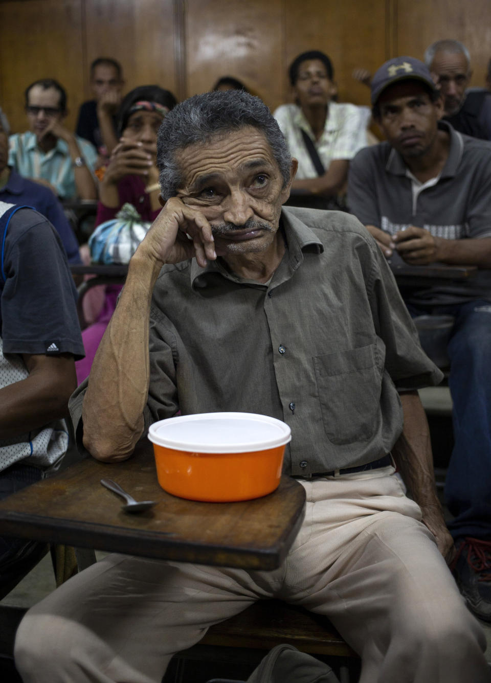 En esta foto del 27 de febrero de 2020 Orlando Blanco, de 68 años, espera que le sirvan comida en un centro religioso en el barrio El Cementario en Caracas, Venezuela. (AP Foto/Ariana Cubillos)