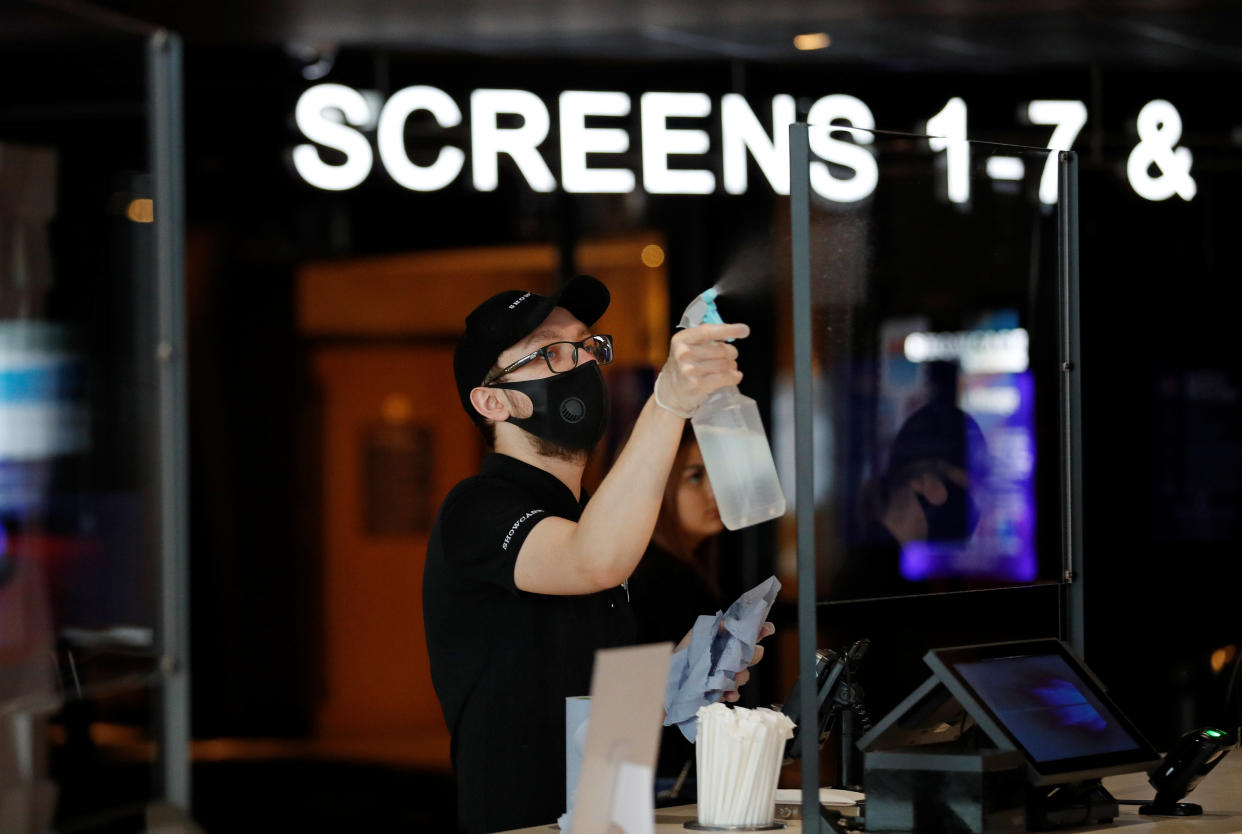 A staff member wearing a face mask cleans a protective screen following the outbreak of the coronavirus disease (COVID-19) at the "Showcase Cinema de Lux" in Coventry, Britain July 10, 2020. REUTERS/Andrew Boyers