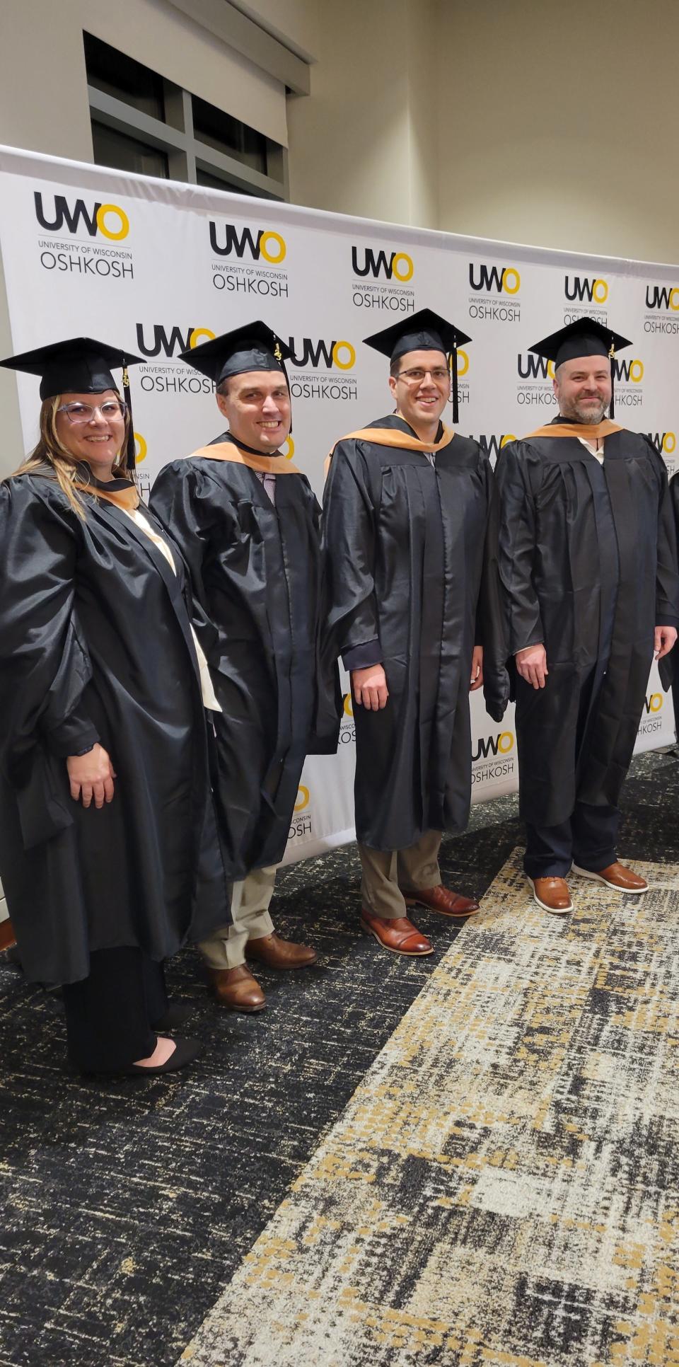 Four of the seven graduates in a cohort of UW-Oshkosh executive MBA students at graduation earlier this year. In June, they each received a $7,900 bill from the university.