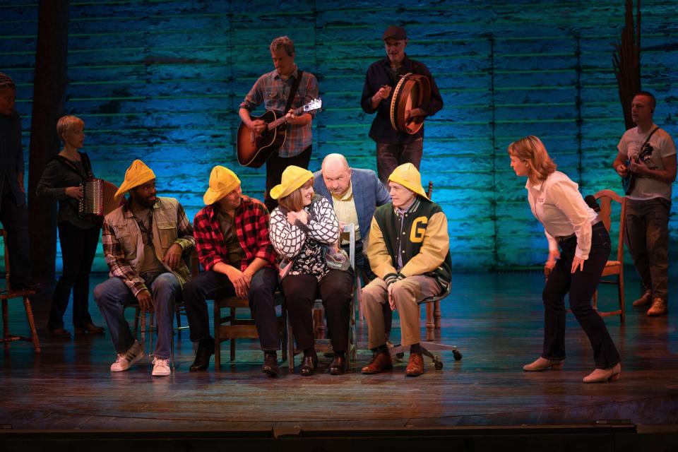 the cast of come from away on stage wearing yellow slicker hats