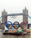 In this handout image provided by LOCOG, Torchbearer 018 Amber Charles stands underneath the giant Olympic Rings on the River Thames outside City Hall during Day 70 of the London 2012 Olympic Torch Relay on July 27, 2012 in London, England. The Olympic Flame is now on Day 70 of a 70-day relay involving 8,000 torchbearers covering 8,000 miles. (Photo by LOCOG via Getty Images)