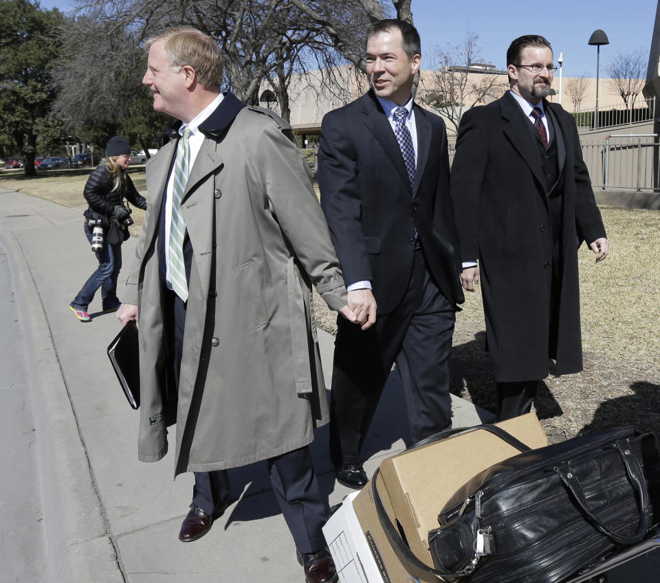 Mark Phariss, left, holds the hand of partner Victor Holmes, center, as they leave the U.S. Federal Courthouse, Wednesday, Feb. 12, 2014, in San Antonio. District Judge Orlando Garcia said Wednesday he would issue a decision later after the two Texas men filed a civil rights lawsuit seeking permission to marry, and a lesbian couple sued to have their marriage recognized. (AP Photo/Eric Gay)