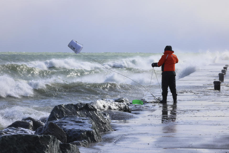 FILE - Rae-Ann Eifert, a lake monitor for the Wisconsin Department of Natural Resources, gathers buckets of water for testing off a Lake Michigan breakwater in Racine, Wis., on Feb. 28, 2024, as part of an effort across the Great Lakes to understand the effects of an iceless winter. Federal meteorologists on Friday, March 8, have made it official: It's the warmest U.S. winter on record by far. (AP Photo/Teresa Crawford, File)