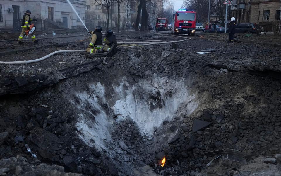 Firefighters work near a crater after a Russian attack