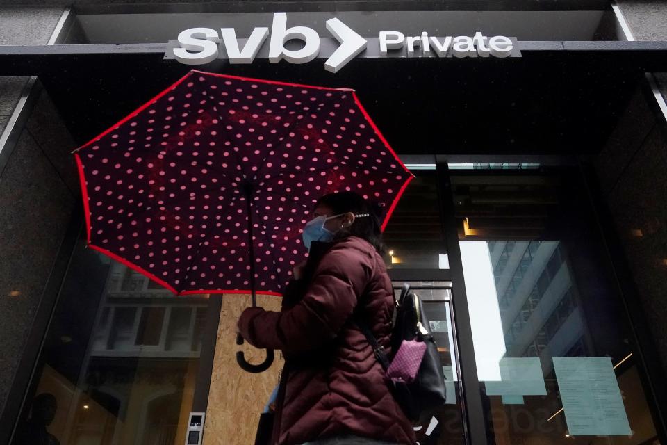 A pedestrian carries an umbrella while walking past a Silicon Valley Bank Private branch in San Francisco, Tuesday, March 14, 2023. (AP Photo/Jeff Chiu)