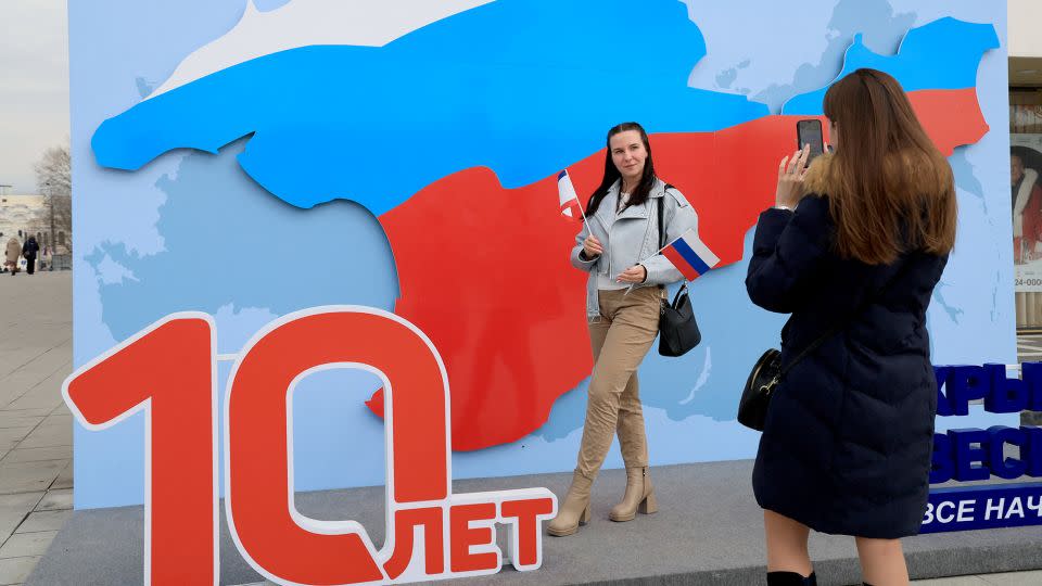 A woman poses for pictures with an artwork featuring the map of Crimea in the colours of the Russian flag, days before the 10th anniversary of Russia's annexation of Crimea, in Simferopol, March 13, 2024. - AFP/Getty Images