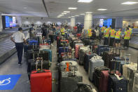 Airport workers arrange rows of suitcases that belong to air travelers at Toronto Pearson International Airport in Mississauga, Ontario, Canada, on Friday, July 22, 2022. (AP Photo/Ted Shaffrey)