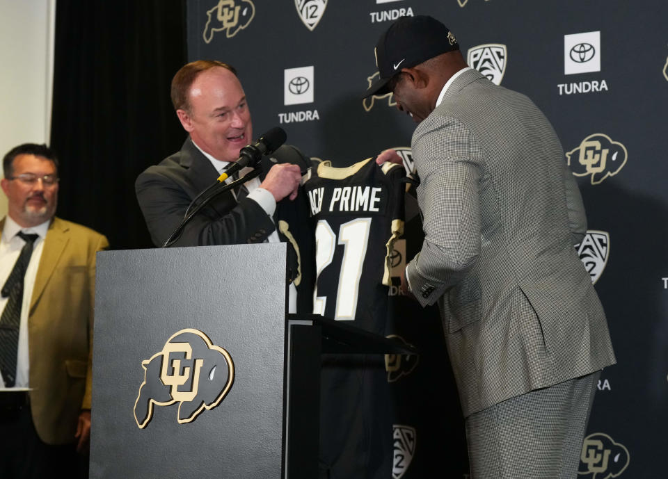 Dec 4, 2022; Boulder, CO, USA; Colorado Buffaloes head coach Deion Sanders is handed a team jersey by athletic director Rick George during a press conference at the Arrow Touchdown Club. Mandatory Credit: Ron Chenoy-USA TODAY Sports