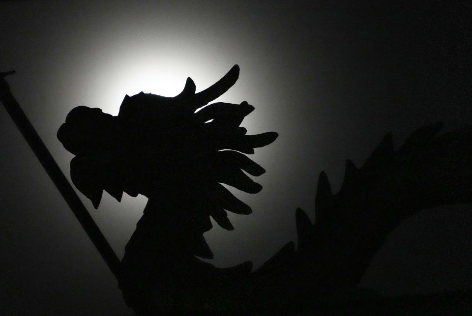 A naga statue is silhouetted against the moon during a total lunar eclipse in front of the Chinese temple in Phnom Penh, Cambodia, Tuesday, Nov. 8, 2022, (AP Photo/Heng Sinith)