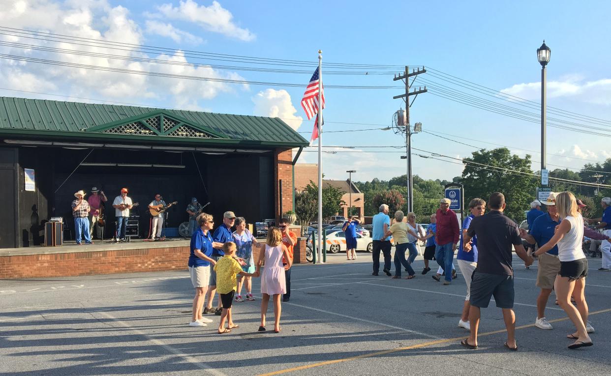 Blue Ridge Tradition performs at the Hendersonville Visitor Center Stage at a 2019 Street Dance while Walt Puckett calls the square dance moves.