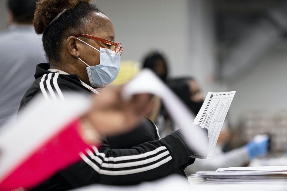 A woman in a mask handles papers