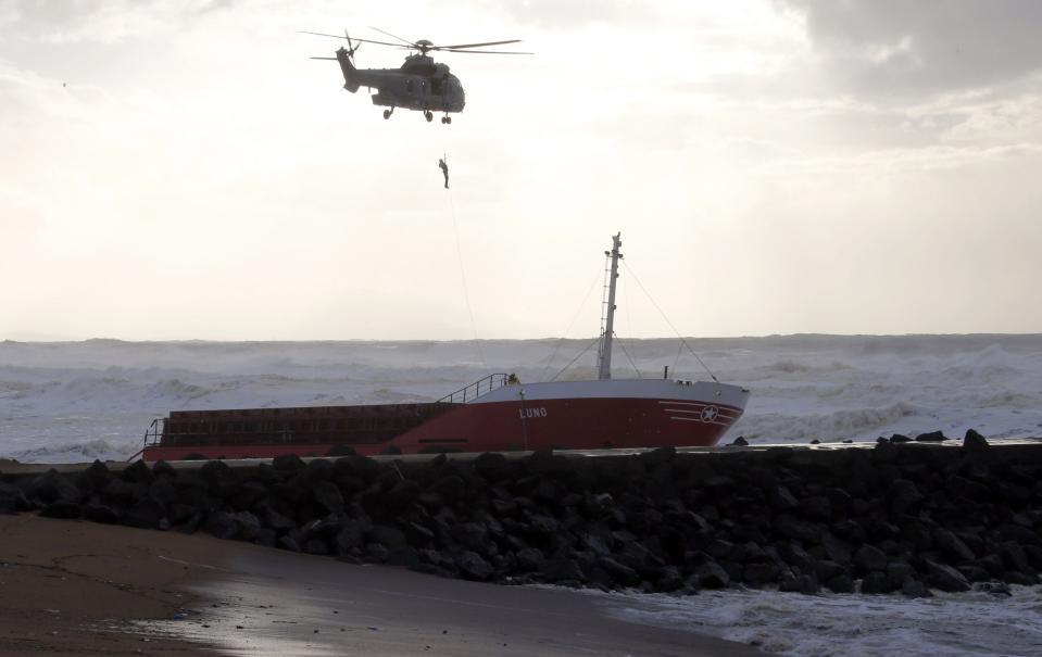 A member of the French military is hoisted by helicopter after inspecting an empty Spanish cargo ship which broke in two on a seawall off the beach in Anglet