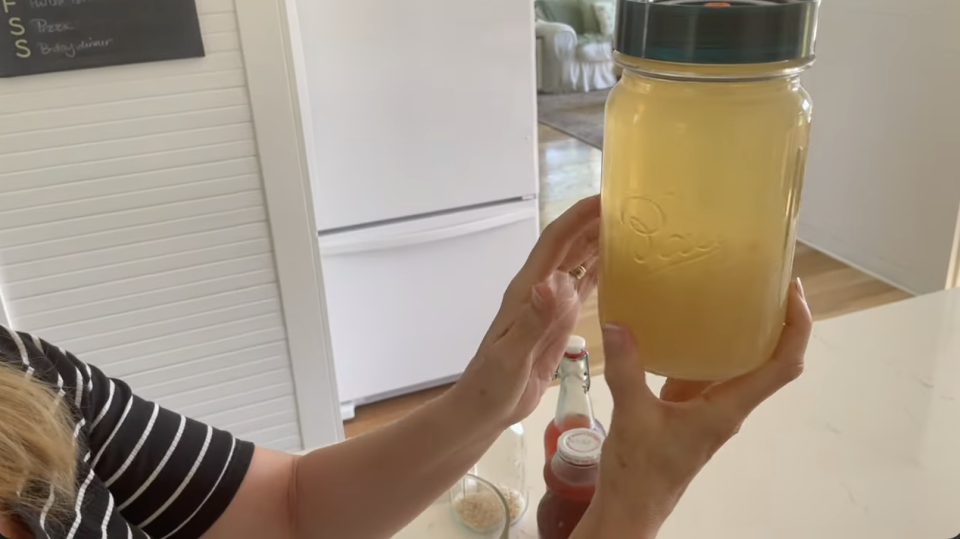 woman holding a bottle of homemade water kefir