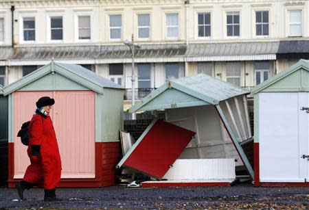 A woman walks past a beach hut destroyed by recent storms on the promenade at Brighton in southern England January 7, 2014. REUTERS/Luke MacGregor