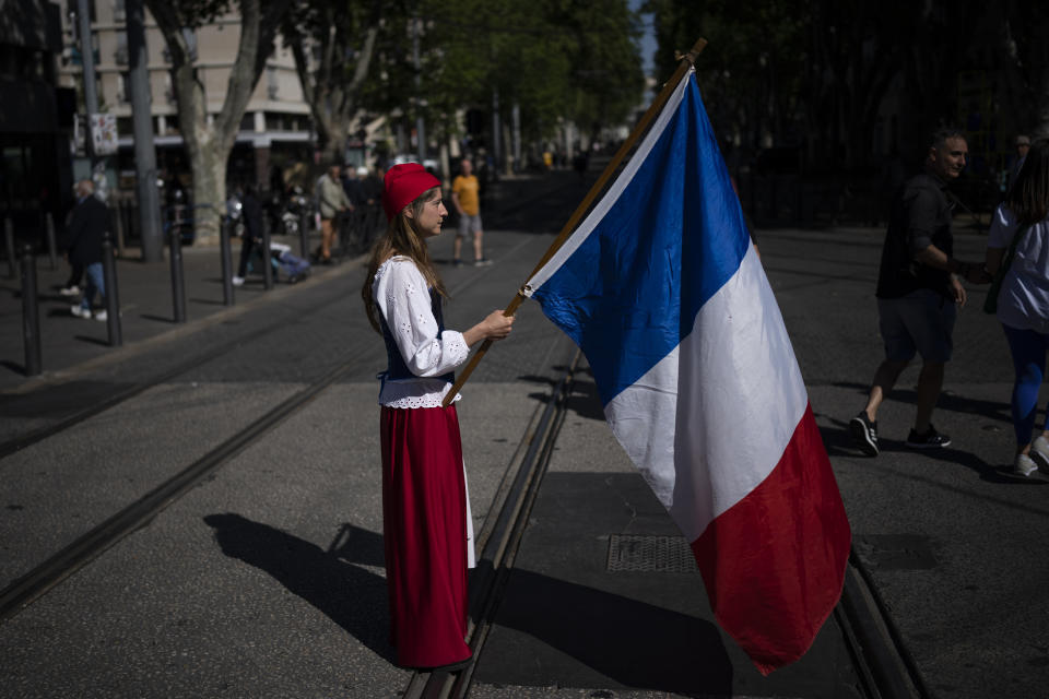A woman dressed up as Marianne, a woman symbol of the French republic since the 1789 revolution, holds a French flag during a May Day demonstration in Marseille, southern France, Sunday, May 1, 2022. May 1 is celebrated as the International Labour Day or May Day across the world. (AP Photo/Daniel Cole)