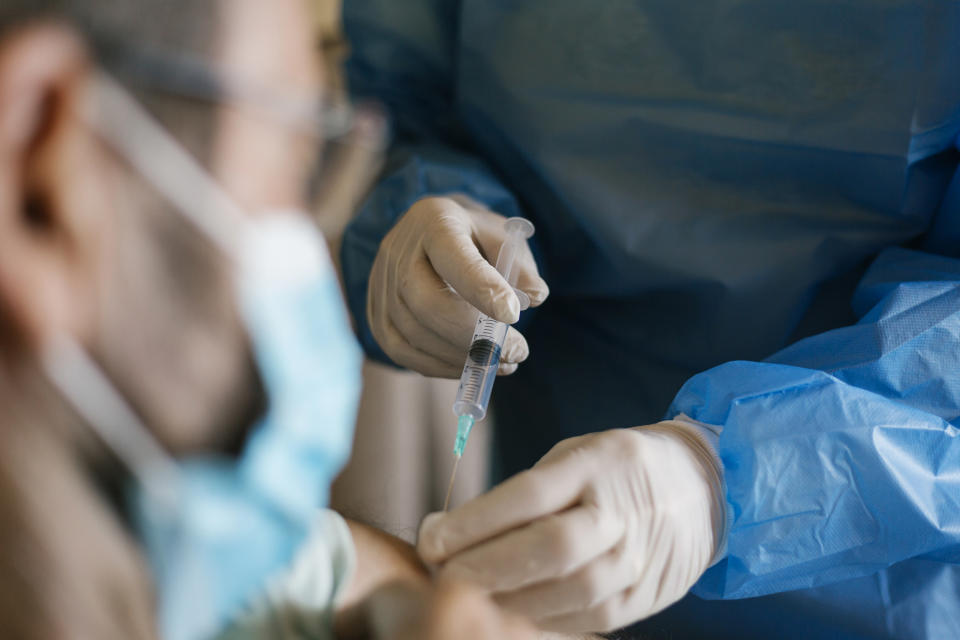 Close-up of a doctor applying the covid-19 vaccine to a senior patient at his home during the isolation. 