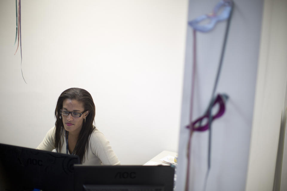 In this photo taken Tuesday, Feb. 5, 2013, samba dancer and a call center supervisor Diana Prado sits at her work desk, in Rio de Janeiro, Brazil. Prado spends her daylight hours working at the call center. At night, she is a samba dancer, or "passista," as they're known in Portuguese, for the Sao Clemente group. Though passistas are unquestionably the star attractions of the world's most iconic Carnival celebrations, they're not on the payroll of the samba school they represent. (AP Photo/Felipe Dana)