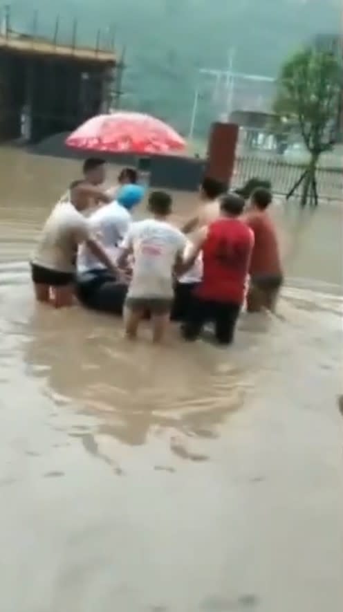 孕婦有早產的跡象，村民合力將她推送至救護車上。（圖／翻攝自人民日報微博）