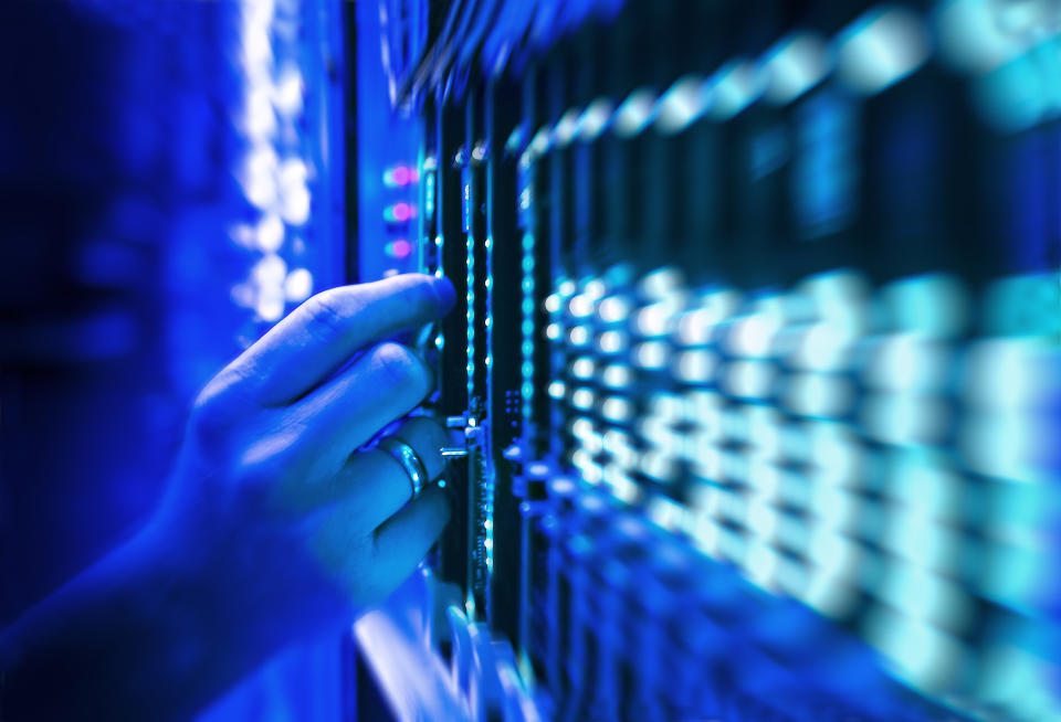 network server technician in data center bathed in blue light