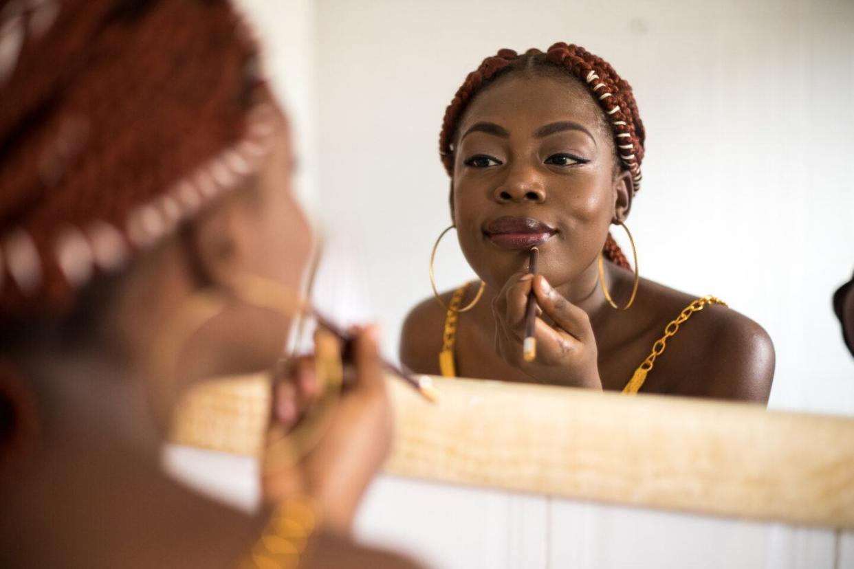 Self-Care: Woman applies lip liner in mirror