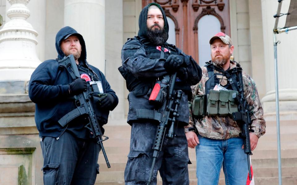 In this file photo taken on April 30, 2020, armed protesters provide security as demonstrators take part in an "American Patriot Rally," organized by Michigan United for Liberty on the steps of the Michigan State Capitol in Lansing, demanding the reopening of businesses. - A far-right movement whose followers have appeared heavily armed at recent US protests has suddenly become one of the biggest worries of law enforcement, after one killed two California police officers. - Jeff Kowalsky/AFP