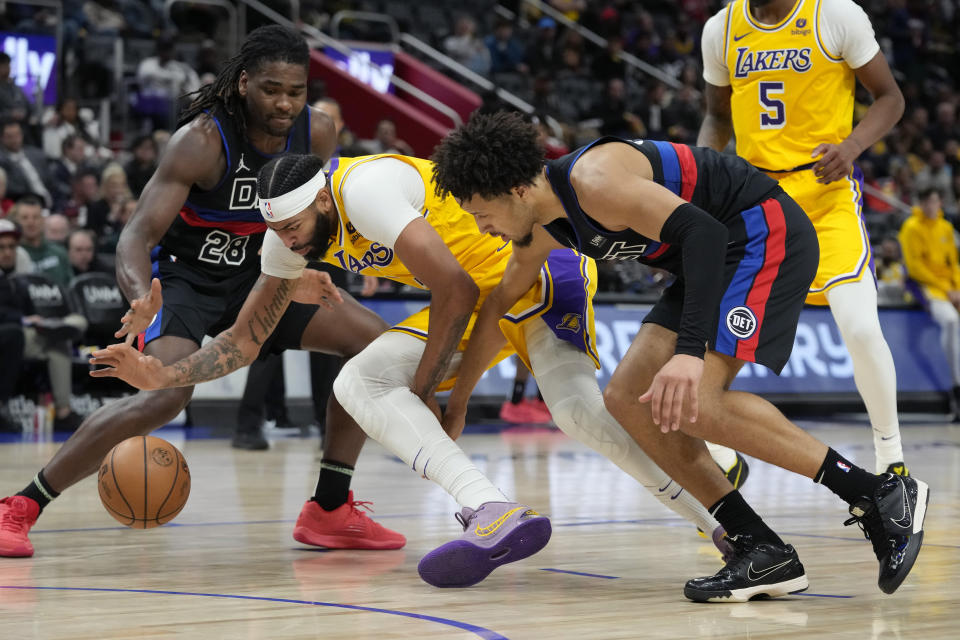 Detroit Pistons guard Cade Cunningham (2) and Los Angeles Lakers forward Anthony Davis (3) chase the loose ball during the first half of an NBA basketball game, Wednesday, Nov. 29, 2023, in Detroit. (AP Photo/Carlos Osorio)