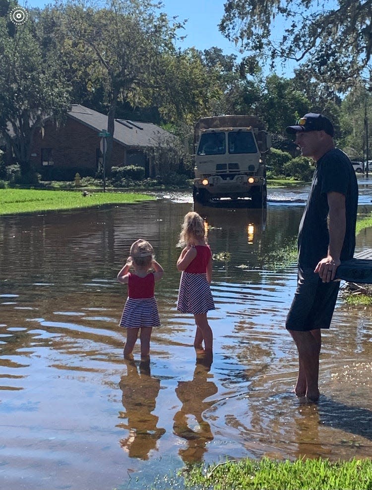Marlie, 2, and Mazie, 4, watch with their father, David Kennedy, as a National Guard truck drives along a flooded street in Bryan Cave Estates in South Daytona.