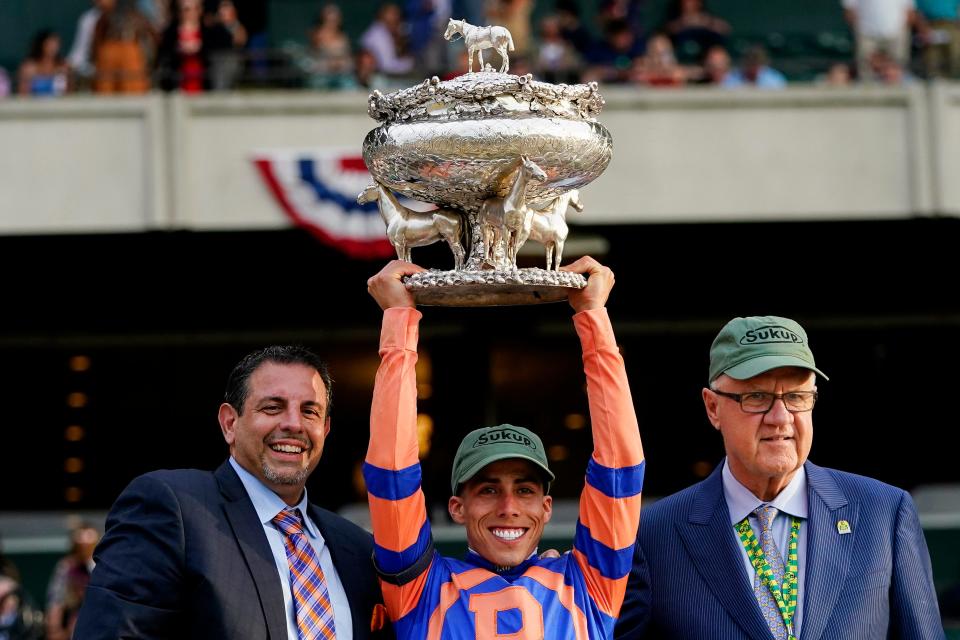 Jockey Irad Ortiz Jr. holds the August Belmont Memorial Cup after Mo Donegal won the Belmont Stakes horse race Saturday, June 11, 2022, at Belmont Park in Elmont, N.Y. With Ortiz are part-owners Mike Repole, left, and Jerry Crawford, right.