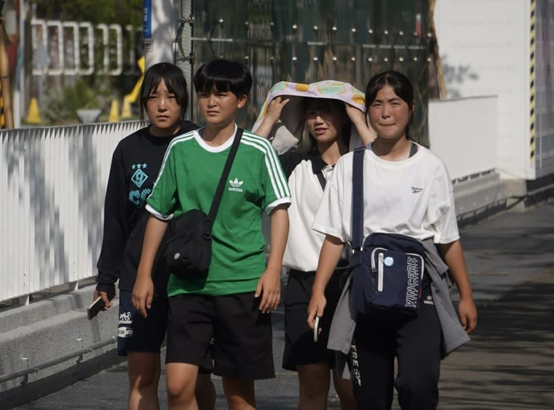 高雄地區高溫炎熱 中央氣象署18日發布高溫資訊，其中高雄市為橙色燈 號，午後對流雲系發展旺盛影響，易有短延時強降 雨。圖為民眾在高雄鹽埕區街頭，試圖用衣物遮擋豔 陽。 中央社記者董俊志攝  113年7月18日 