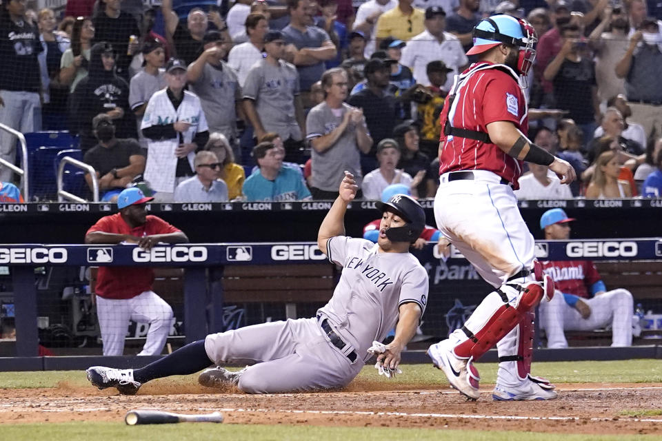 New York Yankees' Giancarlo Stanton, left, scores on a single past Miami Marlins catcher Sandy Leon during the eighth inning of a baseball game, Sunday, Aug. 1, 2021, in Miami. (AP Photo/Lynne Sladky)