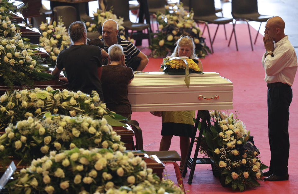 People stand by a small white coffin of a victim of a collapsed highway bridge prior to the start of the funeral service, in Genoa, Italy, Saturday, Aug. 18, 2018. Saturday has been declared a national day of mourning in Italy and includes a state funeral at the industrial port city's fair grounds for those who plunged to their deaths as the 45-meter (150-foot) tall Morandi Bridge gave way Tuesday. (AP Photo/Gregorio Borgia)