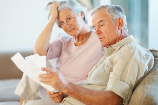 BHYT6R Elderly man with his wife going through documents on couch. Image shot 2009. Exact date unknown. Mistakes Retirees Make b