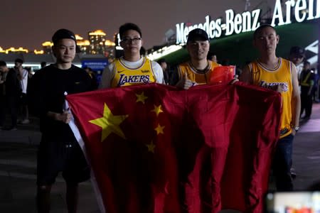 Fans in Los Angeles Lakers jerseys hold Chinese national flags as they pose for pictures outside the Mercedes-Benz Arena before the NBA exhibition game between Brooklyn Nets and Los Angeles Lakers in Shanghai