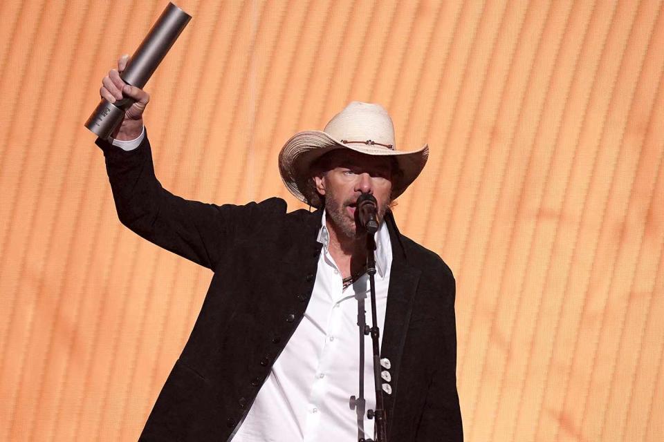 <p>Mickey Bernal/NBC via Getty</p> Toby Keith accepts the Country Icon award on stage during the 2023 People