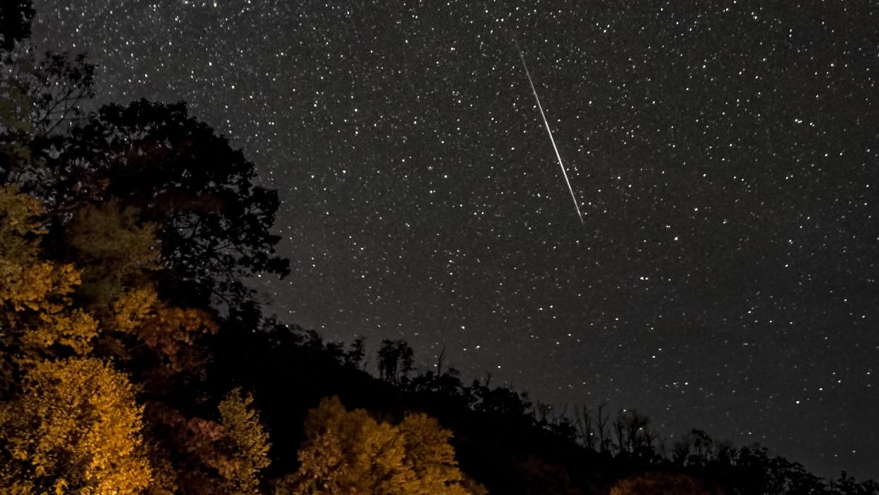  A meteor streaks through a starry sky. 