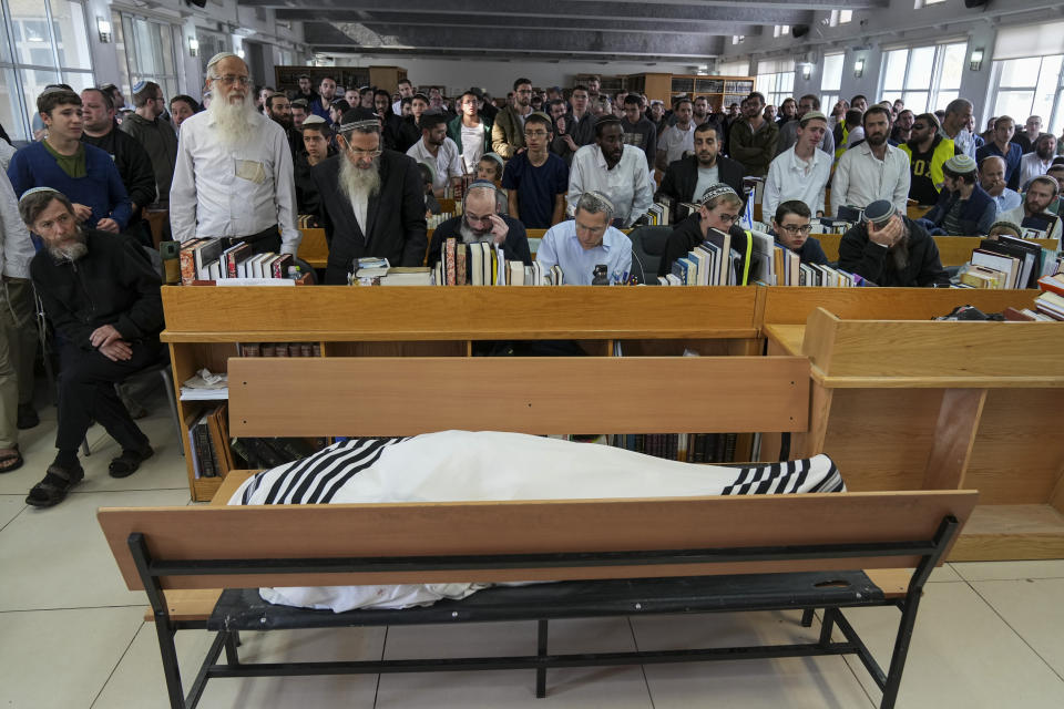 Mourners gather next to the body of rabbi Haim Drukman during his funeral in Merkaz Shapira, a village in southern Israel, Monday, Dec. 26, 2022. Haim Drukman, a prominent rabbi who was one of the founders of Israel's settlement movement, and a former member of Knesset, Israel's parliament, died Sunday. He was 90. Drukman was a leading figure in the religious Zionist movement in Israel, and a major proponent of Jewish settlements in the West Bank, the Gaza Strip and the Sinai Peninsula after Israel captured those territories in the 1967 Mideast war. (AP Photo/Tsafrir Abayov)