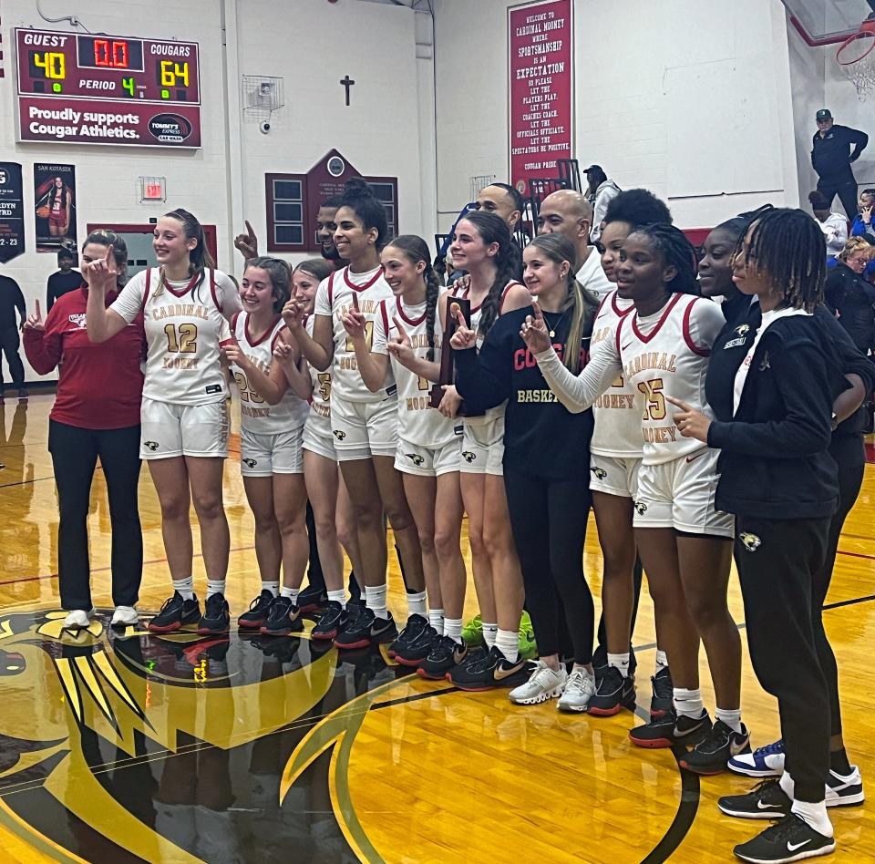 The Cardinal Mooney Catholic High girls basketball team hoists the Class 3A-Region 3 trophy after defeating Tampa Catholic, 64-40, Thursday evening at Patterson Pavilion in Sarasota.