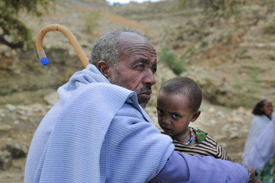 An elderly man sitting with a young boy attends a community meeting in Mai Mekden, in the Tigray region of northern Ethiopia, on Tuesday, Feb. 27, 2024. Once-lush fields lie barren. The Ethiopian region of Tigray is peaceful but war’s effects linger, compounded by drought and a level of aid mismanagement that caused the U.N. and the U.S. to temporarily suspend deliveries last year. (AP Photo/Tesfalem Girmay Assefa)