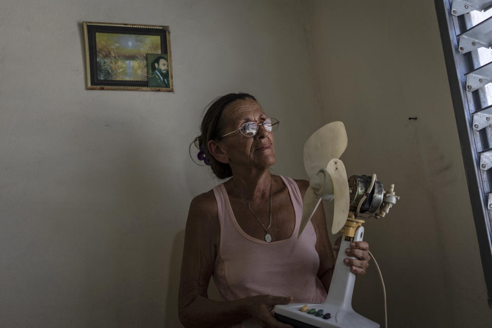 Miriam Cortes poses with her fan next to a photo of Fidel Castro during a planned power outage in Regla, Cuba, on Aug. 1. (Ramon Espinosa / AP)