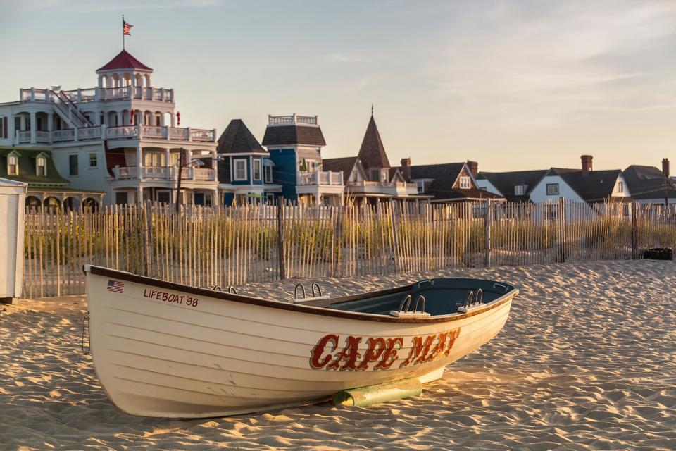 Victorian Homes and hotels line Beach Ave. in Cape May with lifesaving rescue boat on the beach.