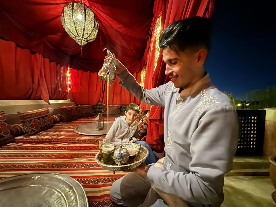 staff member pouring tea in the magic carpet rooftop patio at anayela riad in morocco