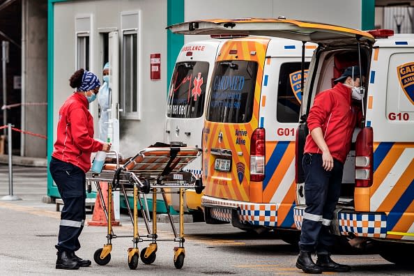 A member of an ambulance crew sanitises a gurney at the emergencies of the Greenacres Hospital in Port Elizabeth, South Africa, near a line of queuing ambulances.