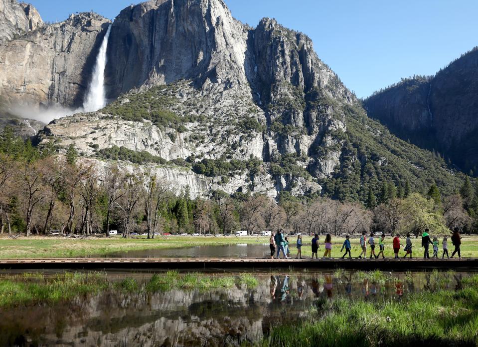 A school group crosses a meadow which is beginning to flood in front of Yosemite Falls in Yosemite Valley, as warming temperatures have increased snowpack runoff, on April 28, 2023 in Yosemite National Park, California