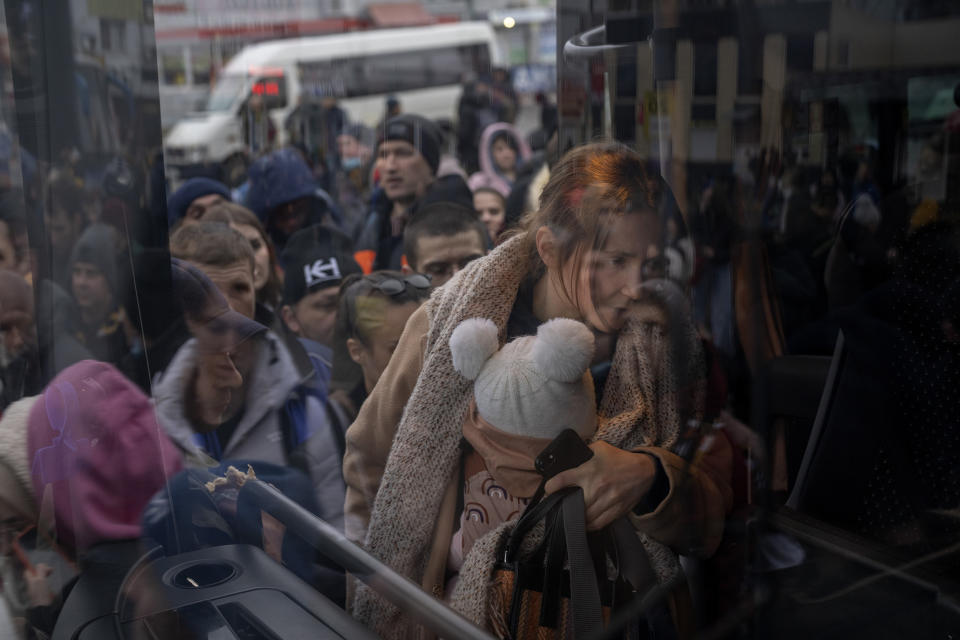 A woman holds her baby as she gets on a bus (Emilio Morenatti / AP)