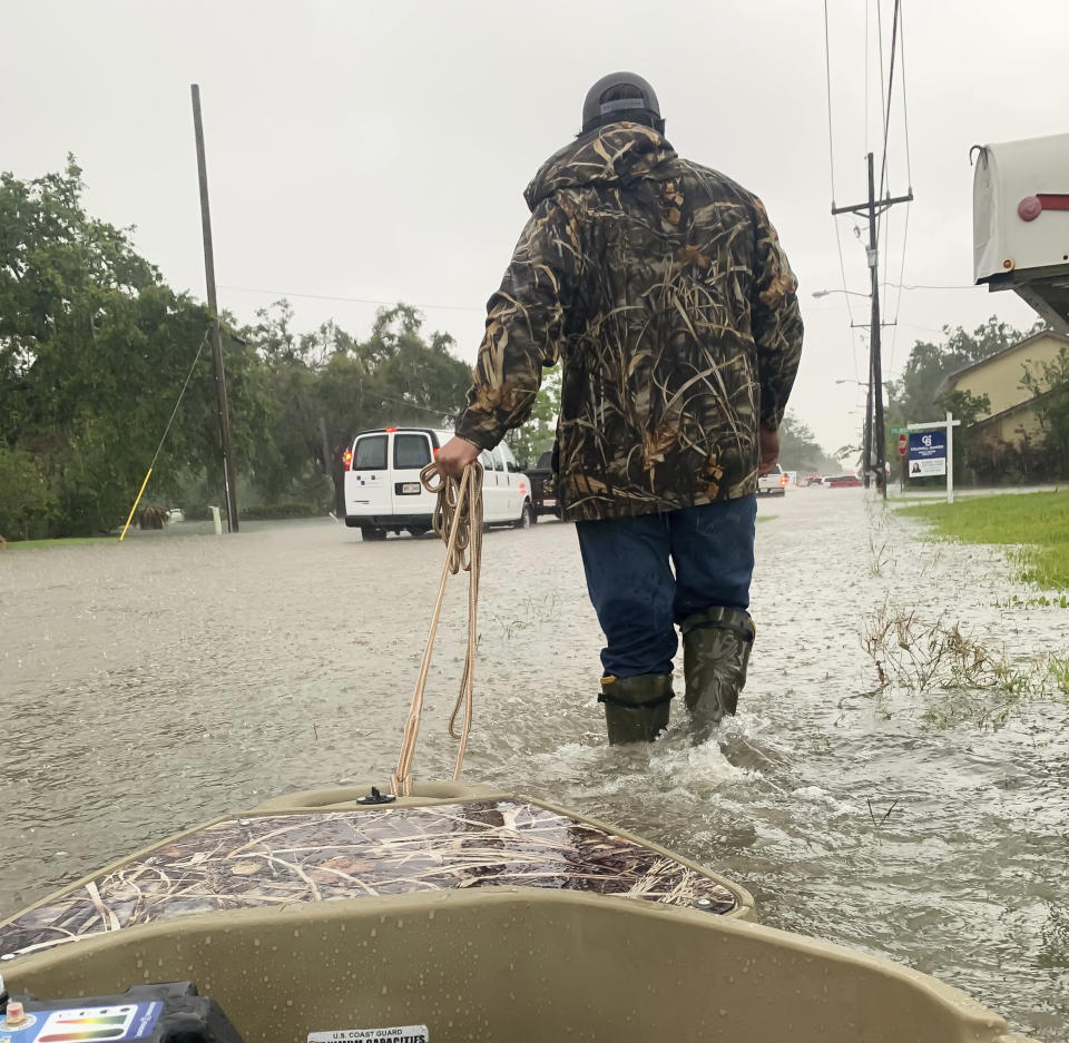 Nick Delgado uses his boat to help a neighbor pick up their kids from schools during heavy rains in Lake Charles, La., Monday, May 17, 2021. (Rick Hickman/American Press via AP)