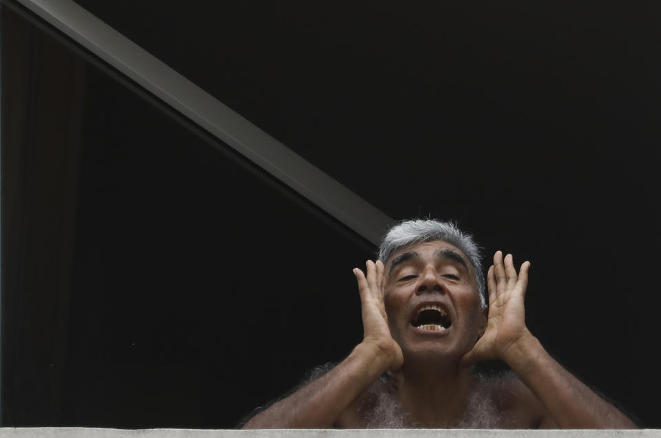 Marcelo Gomez shouts to the press about poor living conditions at a hotel where he is being quarantined by the government in Buenos Aires, Argentina, Wednesday, April 1, 2020. The government placed many Argentines returning from vacation into single hotel rooms where they are not allowed to leave. Many of them are denouncing what they describe as bad treatment, insufficient cleaning conditions, poor food, and no information on how long they will be forced to stay. (AP Photo/Natacha Pisarenko)