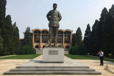 A journalist takes pictures next to a statue of late Chinese Chairman Mao Zedong inside the Party School of the Chinese Communist Party (CPC)'s Central Committee during a government organised visit in Beijing