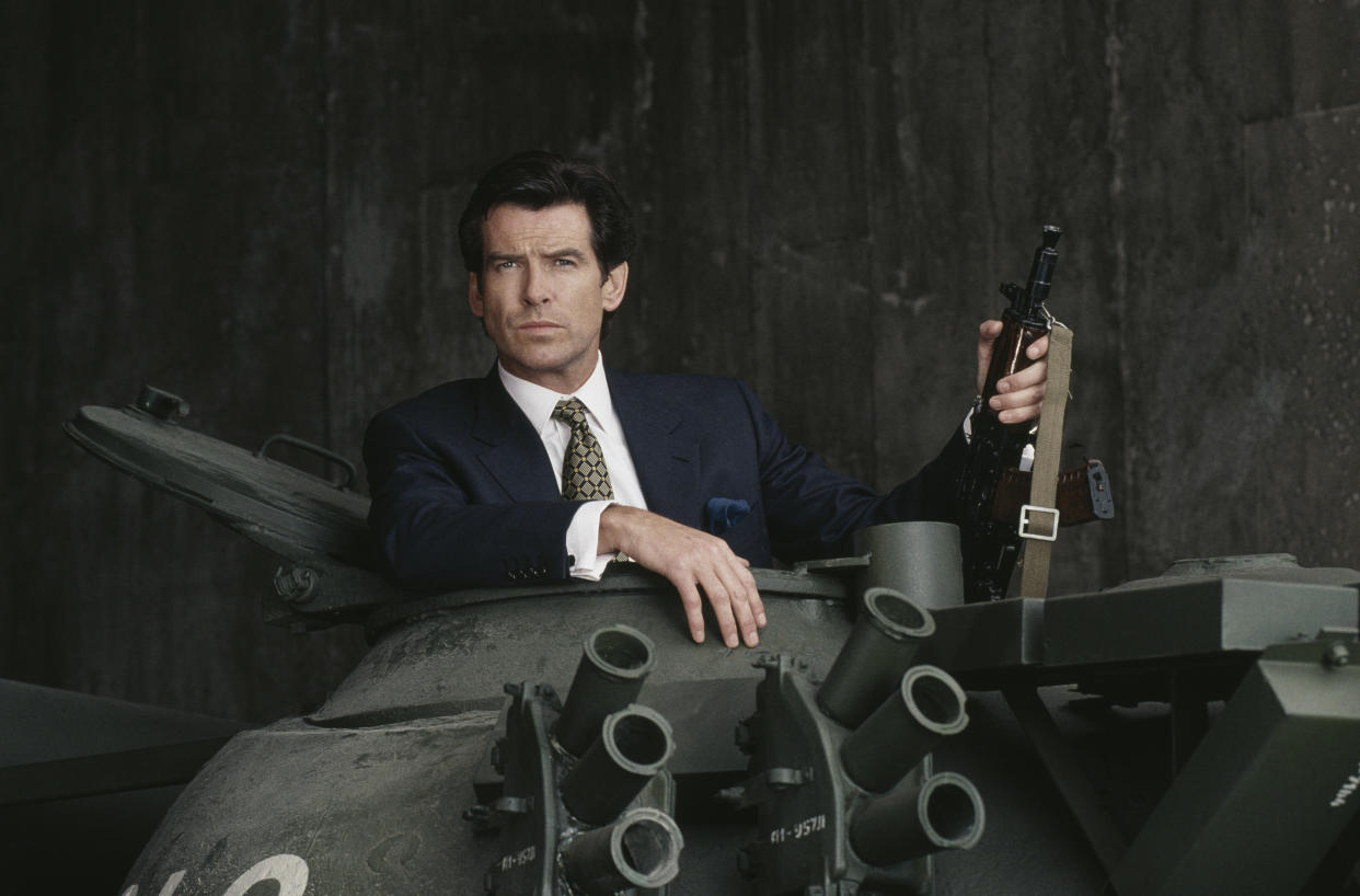 Irish actor Pierce Brosnan poses in the hatch of a Russian T55 Main Battle Tank holding a Kalashnikov automatic rifle, in a publicity still for the James Bond film 'GoldenEye', 1995. (Photo by Keith Hamshere/Getty Images)