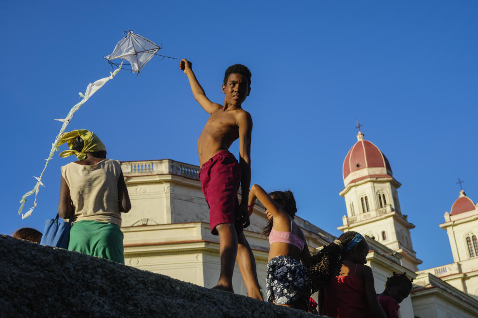 Un niño vuela una cometa fuera del santuario de la Virgen de la Caridad del Cobre en El Cobre, Cuba, el sábado 10 de febrero de 2024. Reconocida por el Vaticano y venerada por católicos y seguidores de las tradiciones de la santería afrocubana, es más que un icono religioso, la Virgen está en el corazón de la identidad cubana y une a compatriotas de la isla caribeña gobernada por el Partido Comunista con los exiliados o quienes emigraron a Estados Unidos. (AP Foto/Ramón Espinosa)