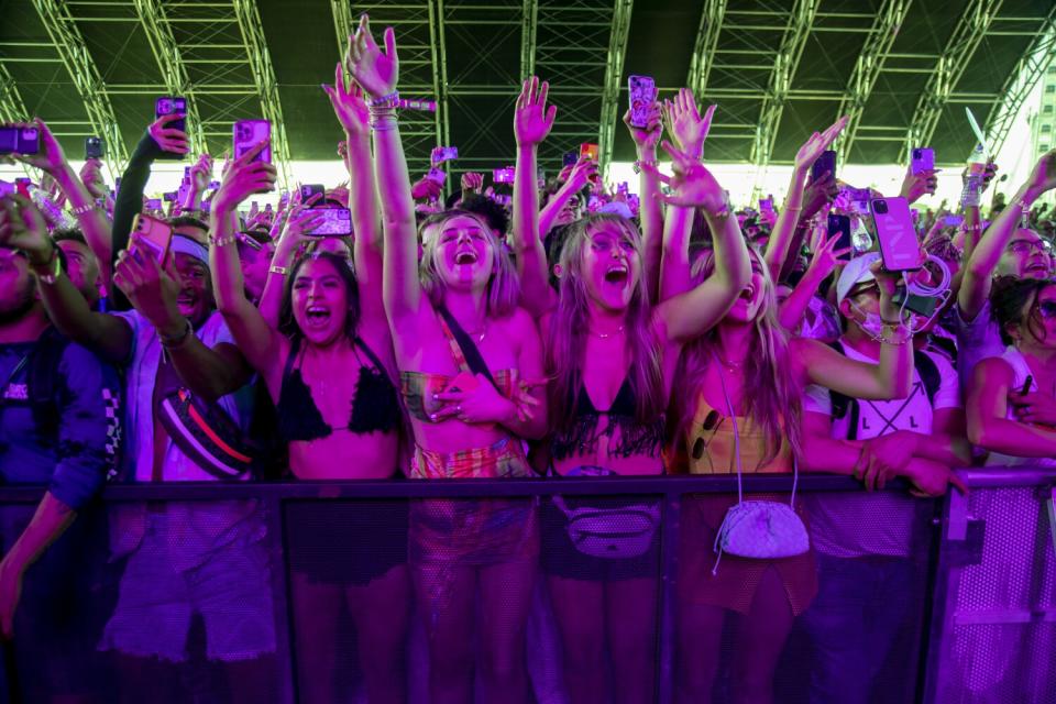 Music fans cheer and hold up their arms during a performance.